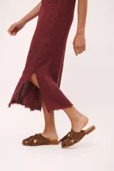 Vestido largo sin mangas, color rojo vibrante, con escote en V y cierre de botones frontal. Presenta tajos laterales y un pequeño aplique bordado de cerezas en el pecho.