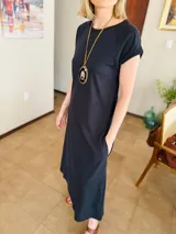 Vestido midi negro de algodón, con mangas cortas, cuello redondo y bolsillos laterales.