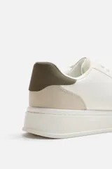 Zapatillas deportivas blancas con detalle en color gris en el talón y suela con plataforma.