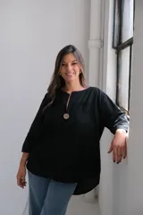 Blusa negra de corte holgado, con cuello redondo y abertura en V con botón de madera. Presenta bordados con motivos de paisley.