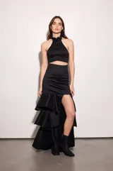 Falda larga negra de tafeta con cintura ajustada, tajo lateral y volados escalonados.