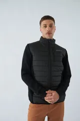 Campera negra con cuerpo acolchado de nylon y mangas de felpa. Tiene cuello alto, cierre frontal, bolsillos laterales con cierre, logo estampado en el pecho y logo de goma en la manga.