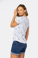 Remera blanca estampada con flores azules y beige, de manga corta y cuello redondo.