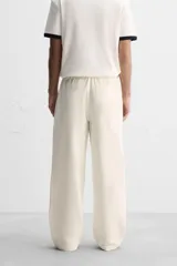 Pantalón color crema de corte amplio, con cintura elástica ajustable con cordón, bolsillos laterales y trasero, cierre frontal con cremallera y botón.