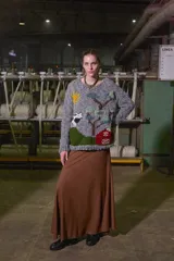 Sweater tejido de lana color gris con cuello redondo y puños acanalados. Presenta un diseño bordado a mano con motivos campestres: sol, vaca, árbol y granero.