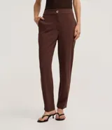 Pantalón zanahoria de poliéster color marrón, de cintura alta, con cierre tradicional, bolsillos traseros y botón metalizado con efecto martillado.