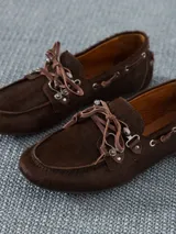 Zapato estilo mocasín acordonado, confeccionado en pelo color marrón con interior forrado en cuero vacuno. Lleva apliques metálicos en níquel.