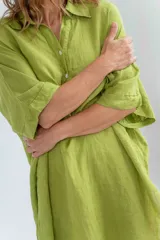 Vestido blanco de lino, corte holgado, con cuello camisero, mangas 3/4 y aberturas laterales.