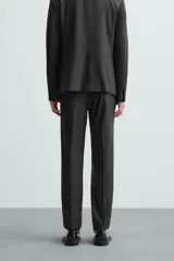 Pantalón de vestir gris oscuro, corte slim fit, con bolsillos laterales y traseros de ojal. Cierre frontal con cremallera y botón.