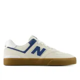 Championes New Balance modelo NM574 VRU, color beige con detalles en azul y blanco, suela de goma marrón y logo "N" en los laterales.
