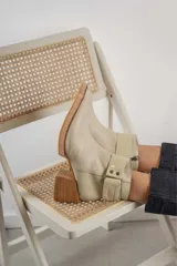 Bota corta de cuero marrón con puntera redondeada y taco cuadrado. Presenta una correa con hebilla alrededor del tobillo y cierre lateral.