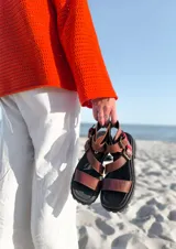 Sandalias de cuero color marrón chocolate con detalles en rojo, base color chocolate y hebillas ajustables. Hechas a mano en Uruguay.