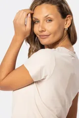 Remera manga corta color beige con cuello redondo y estampado de una mujer en la playa.
