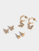 Set de tres pares de aros dorados con forma de mariposa: un par de aros tipo botón con mariposas lisas, un par de aros tipo botón con mariposas con incrustaciones de strass y un par de aros colgantes con mariposas con incrustaciones de strass.