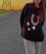 Sweater marrón tejido a mano con diseño de herradura fucsia y estrellas crudas.