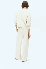 Pantalón de felpa color crema, de corte relajado con cintura elástica fruncida, bolsillos laterales discretos y piernas rectas.