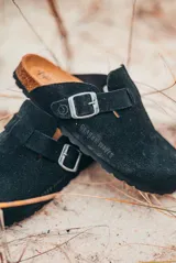 Zuecos negros de cuero con hebilla metálica ajustable y plantilla anatómica de corcho.