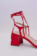 Sandalias rojas de cuero con tiras finas para atar al tobillo y tacón cuadrado.