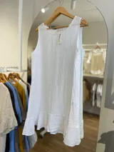 Vestido corto blanco de lino, sin mangas, con escote redondo y volado en el ruedo.