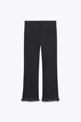Pantalón negro de tiro alto con corte mini flare y volantes con estampado de lunares en el bajo.
