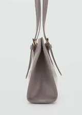 Bolso tipo tote de color gris con efecto piel, forro interior, asa corta y asa de hombro. Presenta cierre a presión y cierre de cremallera, bolsillo interior, hebillas decorativas.
