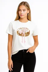 Remera blanca de manga corta con estampado de un cinnamon roll con un lazo rosa.