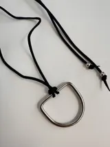 Gargantilla con tiento de cuero sintético marrón y dije de bronce con forma de estribo.