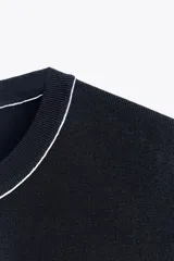 Top de punto color crema, de cuello redondo y manga corta con detalle de vivos a contraste en cuello y hombros.