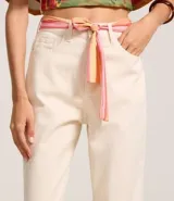 Pantalón mom color crudo confeccionado en sarga de algodón BCI, con bolsillos delanteros y traseros, cierre con botón y cremallera, y pañuelo estampado a modo de cinturón.