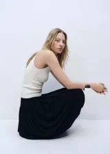 Musculosa blanca de tejido de punto fino, sin mangas y cuello redondo. Diseño entallado.