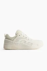 Zapatillas deportivas de estilo skate color crema, confeccionadas en malla y tejido revestido. Presentan cuello y lengüeta acolchados, cordones y trabilla trasera. Forro de tejido rizado y plantillas de piqué. Suela con diseño y grosor de 4,1 cm.