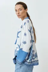 Kimono blanco con estampado floral azul, con mangas 3/4 y cierre frontal con cordón.