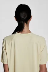 Remera deportiva color crema de tejido funcional con tecnología DryMove™, corte holgado, cuello redondo y mangas cortas raglán.