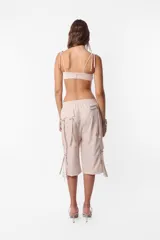 Conjunto de top y short color beige confeccionado en tela brillante. El top cuenta con arco metálico en el busto, tiras para atar en el hombro y ganchos lenceros en la espalda. El short es de tiro alto con cintura elastizada y bolsillos laterales.