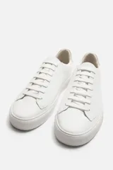 Zapatilla urbana de cuero sintético color negro, con cordones y suela de goma color crema.