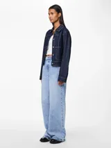 Chaqueta de denim azul oscuro con cuello camisero, cierre frontal con botones metálicos con forma de corazón, bolsillos de parche en el pecho y mangas largas con puños abotonados.