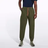 Pantalón jogging color verde oliva confeccionado en nylon reciclado con tecnología DWR (Durable Water Resistance). Cuenta con cintura y puños elásticos, cordón de ajuste naranja, dos bolsillos laterales abiertos y un bolsillo con cierre en la parte superior.