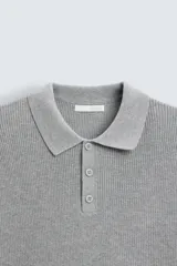 Polo marrón de corte relaxed fit, tejido en punto de algodón. Tiene cuello solapa con cierre frontal de botonadura, manga larga y acabados en rib.