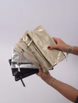 Sobre de mano color crema, con cierre de cremallera y tira de cuero para sujetar a la muñeca.