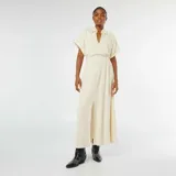 Vestido midi color beige, con cuello tipo camisa, mangas cortas, abotonado al frente y tajo en la falda.