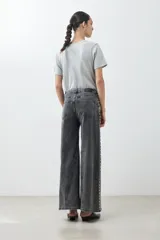 Pantalón de jean gris oscuro, corte wide leg, con tachas plateadas en los laterales.