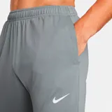 Pantalón largo deportivo Nike Challenger Knit para hombre, color gris con logo blanco en el muslo izquierdo. Corte ajustado con cintura elástica y cordón ajustable. Cuenta con bolsillos laterales y cierres en los tobillos.