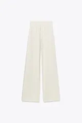 Pantalón de tiro alto color crema, de corte palazzo, con cinturón ancho de tela con hebilla metálica.
