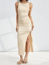 Vestido midi beige ajustado al cuerpo, sin mangas y con escote redondo. Presenta un frunce lateral que genera un drapeado y una abertura alta en la pierna.
