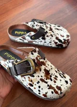 Zuecos con capellada de cuero con estampado animal print en tonos marrones y negros, con hebilla metálica color bronce y suela de goma.