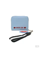 Billetera tipo monedero de color celeste claro, con cierre de cremallera y detalle frontal con texto 'MON AMOUR' en un parche blanco. Incluye un llavero desmontable con forma de labios rojos y una correa de mano negra con franjas blancas.