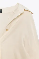Camisa color crema de manga larga con cuello solapa y cierre frontal con botones.