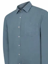 Camisa de manga larga azul con cuello clásico, cierre con botones y bolsillo en el pecho.