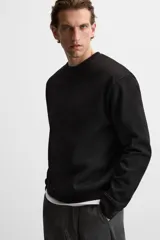 Sudadera negra de corte holgado, cuello redondo y mangas largas con puños acanalados.