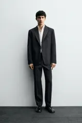 Pantalón de vestir negro de corte recto, con bolsillos laterales y traseros de doble vivo con botón. Cierre frontal con cremallera y gancho metálico.